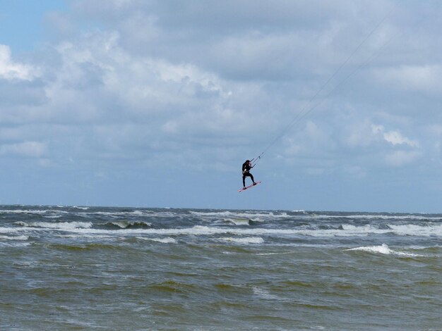 Foto man surft in de zee tegen de lucht