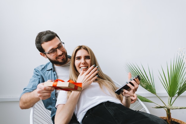 Man surprised her girlfriend with gift, happy couple celebrating valentines day or anniversary