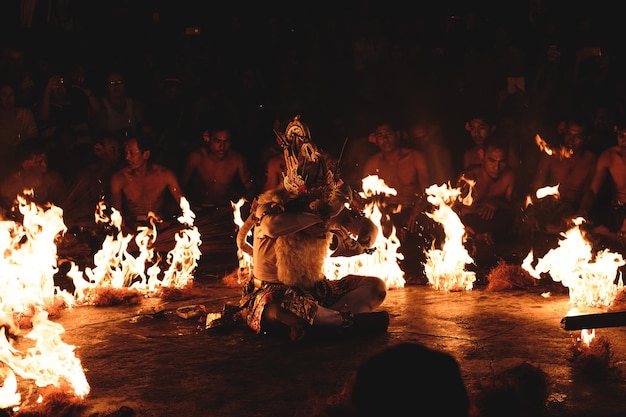 Photo man surrounded by fire and people during traditional festival at night