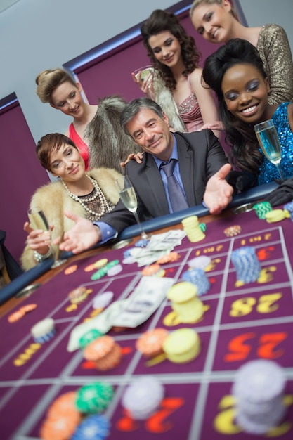 Foto uomo circondato da donne al tavolo della roulette