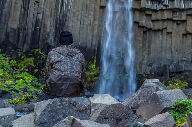 Un uomo nella cascata di svartifoss, la cascata più bella dell'islanda meridionale