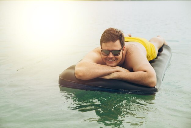 Man swimming on mattress in sea