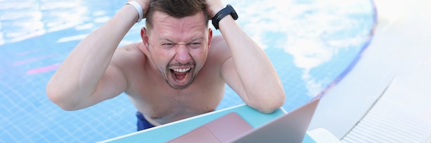 Man swimming in pool and tearing his hair in front of laptop screen