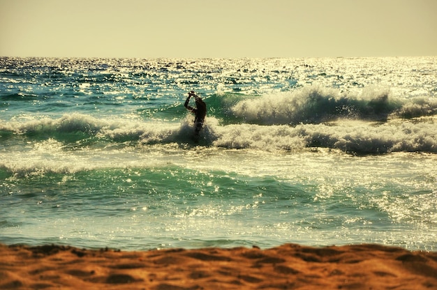 Photo man swimming in sea against sky on sunny day