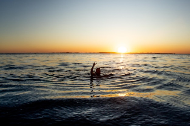 夕日の海で泳いでいる男