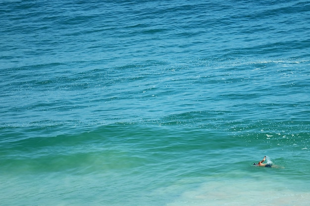 Man swimming in the vibrant color turquoise blue Atlantic ocean