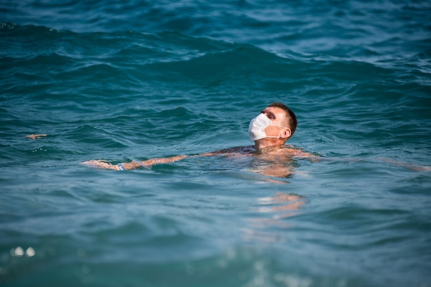 a man swims in the open sea wearing a mask during the covid 19 flu epidemic