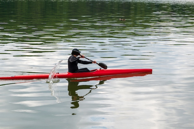 Foto l'uomo nuota in un kayak rosso in uno stagno