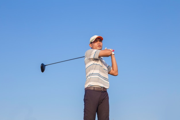 Man Swinging Golf Club with Blue Sky Background