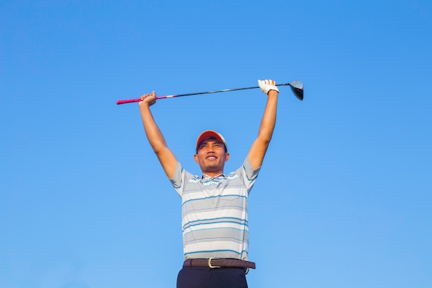 Man Swinging Golf Club with Blue Sky