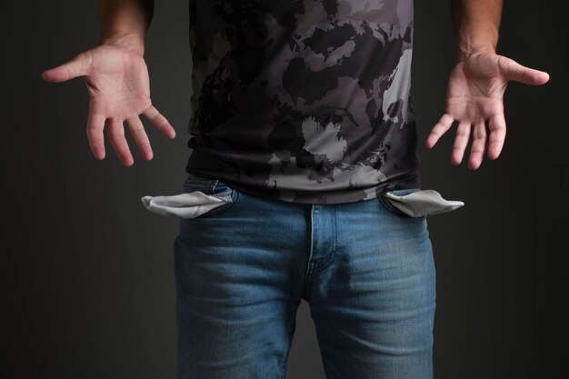 Man in T shirt and jeans with turned out empty pocketsConcept of bankruptcy and poverty