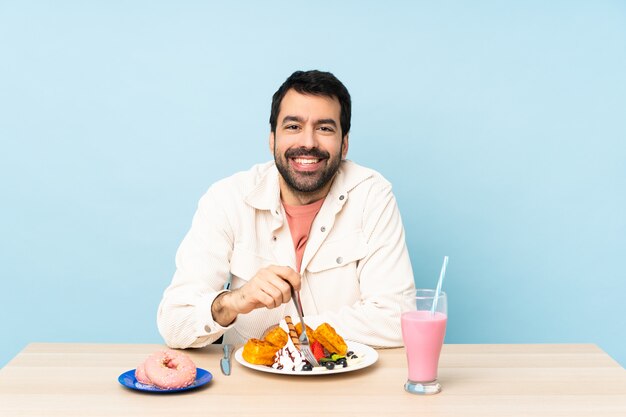 Man at a table having breakfast waffles and a milkshake