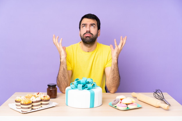 Photo man in a table with a big cake frustrated by a bad situation