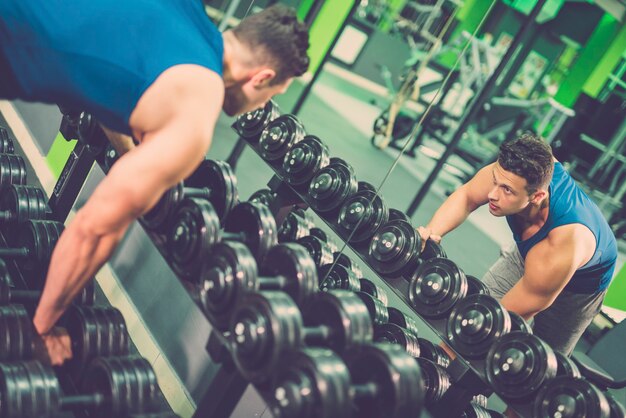 The man take a dumbbell in the gym