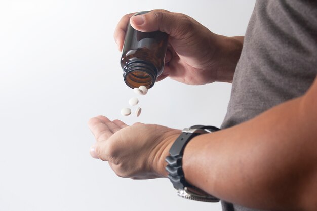 Man take madicine pill from bottle to hand