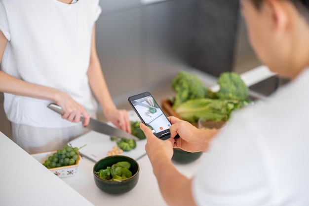 Man take video on smartphone of girl cook salad