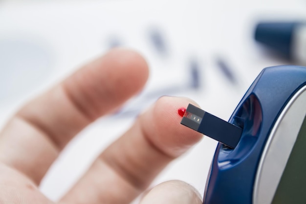 Man takes blood using the test strip for checking blood sugar level by blood glucose meter