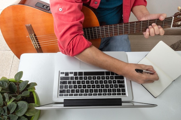 Man takes notes from an online guitar class at home