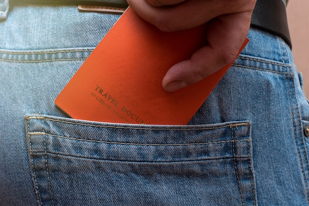 A man takes out his travel document from the back pocket of jeans.