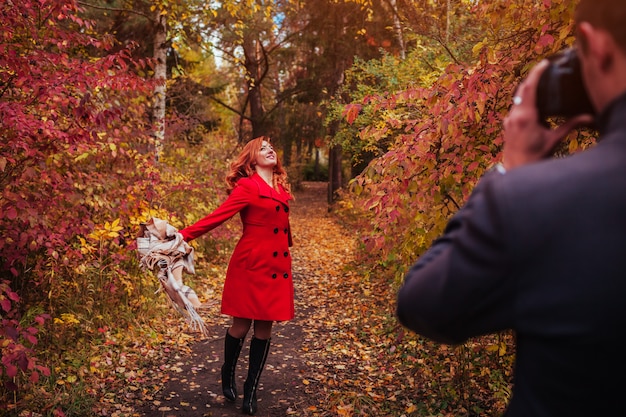 L'uomo scatta una foto della sua ragazza utilizzando la fotocamera nella foresta di autunno