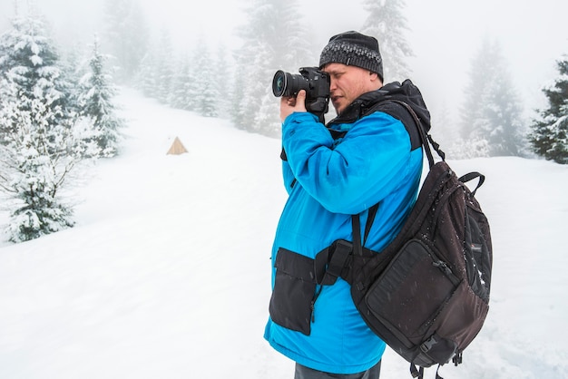 A man takes pictures of something or someone standing in a snowy forest. beautiful winter nature. Photographer in the snowy forest