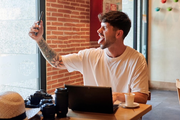 男はリモートで作業しながらコーヒーショップで自画像を取ります