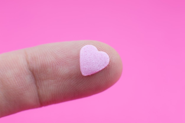 Man takes small Pink heart on pink background. Saint Valentine's day concept. Love and romantic footage.  Beautiful warm wallpaper with love. Soft focus.