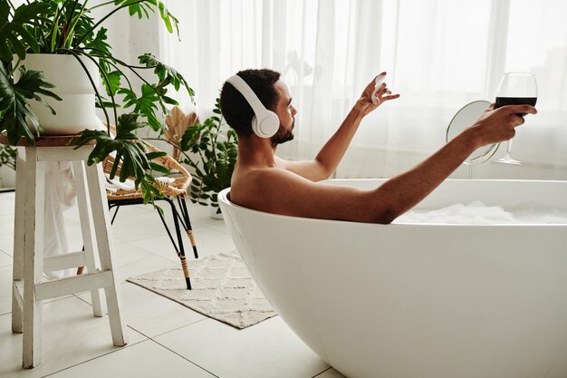 Man taking a bath with glass of wine