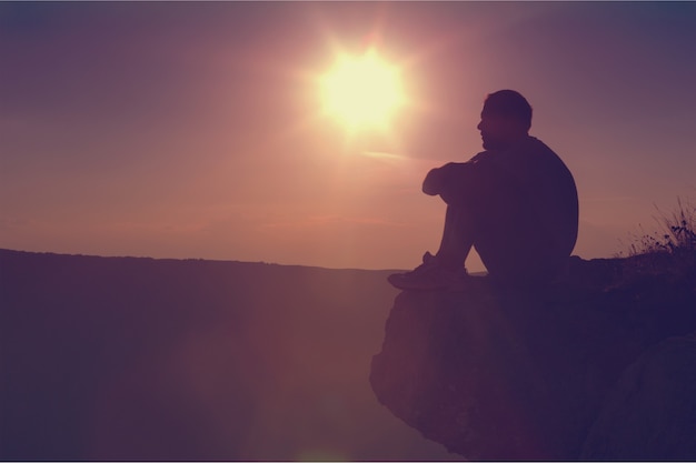 Man taking a break and relax in a meadow in the wonderful warm light of the sunset