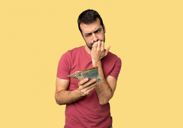 Man taking a lot of money having doubts on isolated yellow background