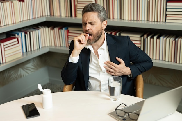 Man taking a medicine pill from headache migraine tired man suffering from headache after computer w