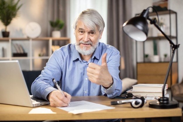 Man taking notes at desk with computer in remote office