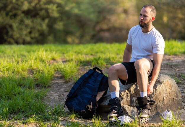 Man taking off inline skates while sitting in a park