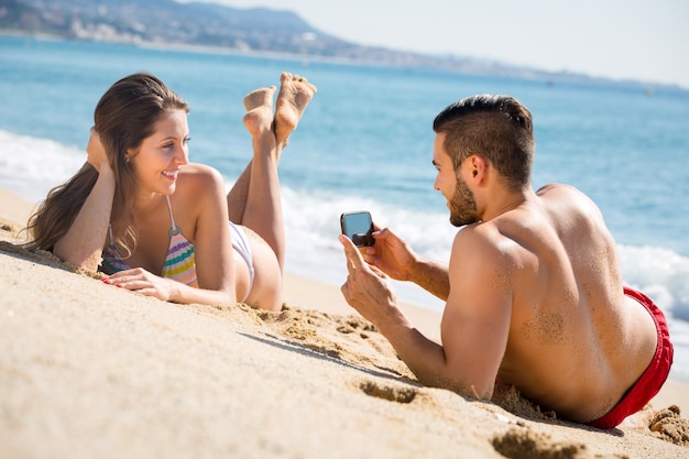 Man taking photo of woman on beach