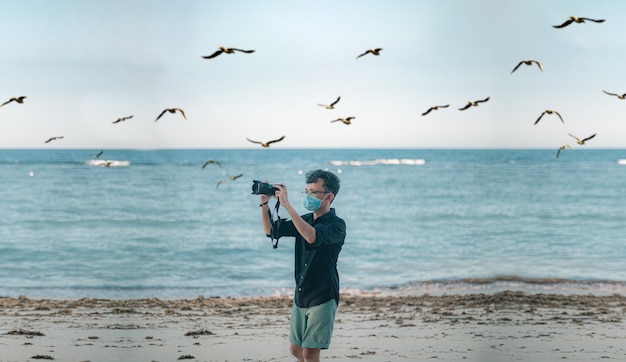 Photo man taking picture on a beach aesthetic