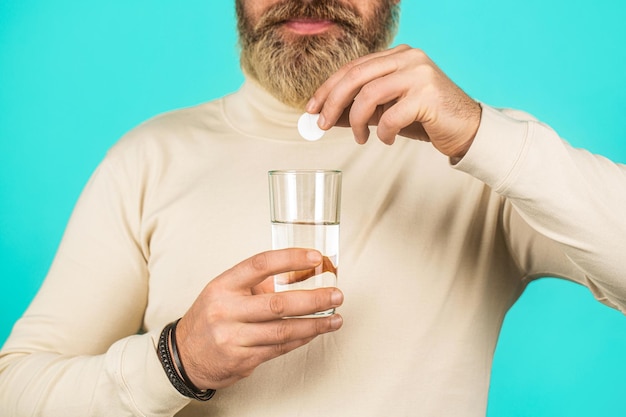 Man taking pill against headache Male taking a pill with a glass of water Man take some pills