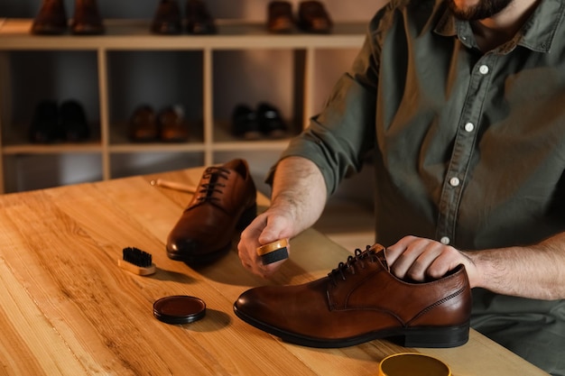 Фото Мужчина профессионально ухаживает за коричневыми кожаными туфлями в мастерской крупным планом