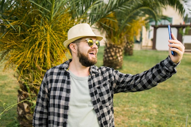 Uomo che prende selfie ritratto su sfondo di palma felice ragazzo millenario godendo le vacanze estive