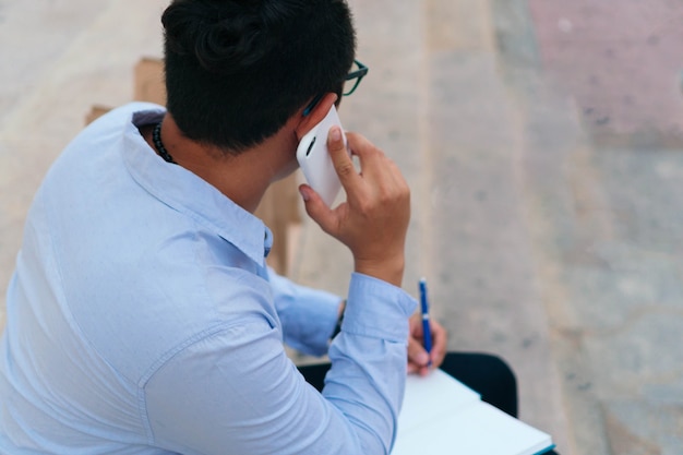 Man talking on cell phone and taking notes in the open air