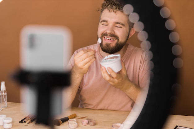 Man talking on cosmetics holding a makeup tools while recording his video guy making video for his b