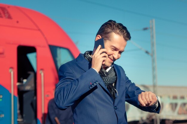 Foto uomo che parla al cellulare mentre è in piedi contro il treno