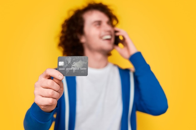 Фото Мужчина разговаривает по телефону и показывает кредитную карту