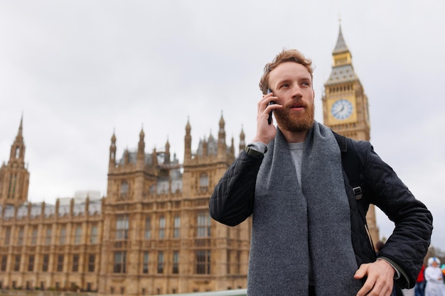 ロンドンのビッグ ベンの近くに立って電話で話している男性