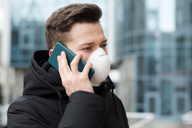 Foto equipaggi la conversazione sul telefono mentre indossano la maschera medica