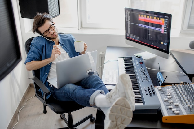 Man talking on the phone and working on a laptop at the studio