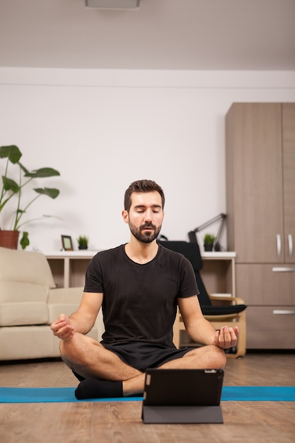 Man talking on video call with his girl while he's working out yoga poses in the living room