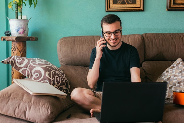 Man talks on his mobile phone at home sitting on a sofa