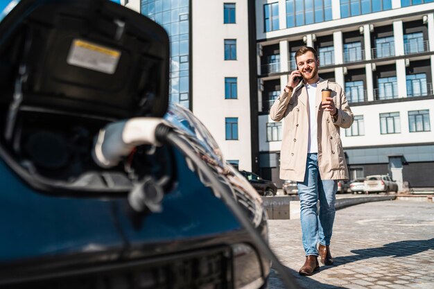 Man talks on the phone when his car is charging at the station