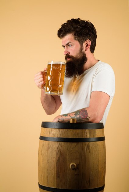 Foto uomo che assaggia birra alla spina, pub e bar, concetto di birrificio, l'uomo tiene una tazza di bevanda, il birraio felice tiene