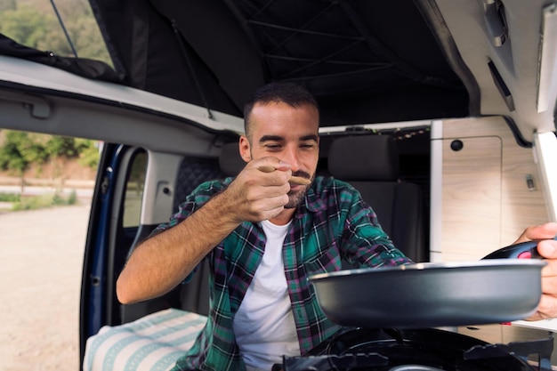 Man tasting food he is cooking in his camper van